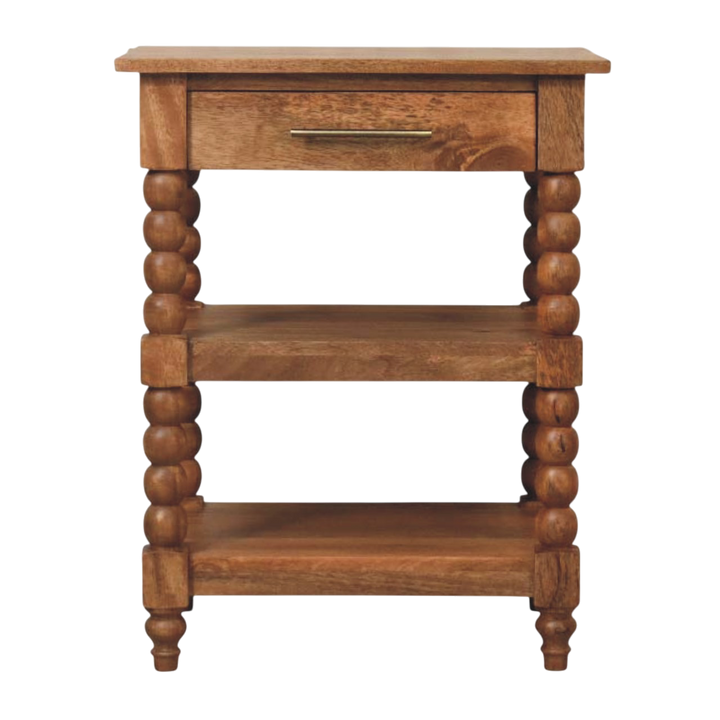 Langham Side Table in Amber, front view. Amber hardwood with carved spindle legs and two open shelves.