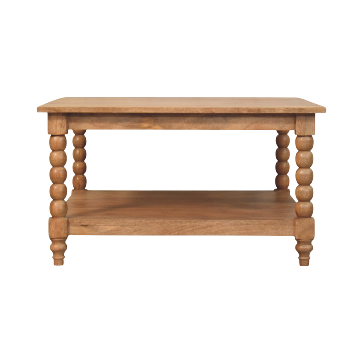 Langham Square Coffee Table in Almond, front view. Almond hardwood with carved spindle legs and an open lower shelf.
