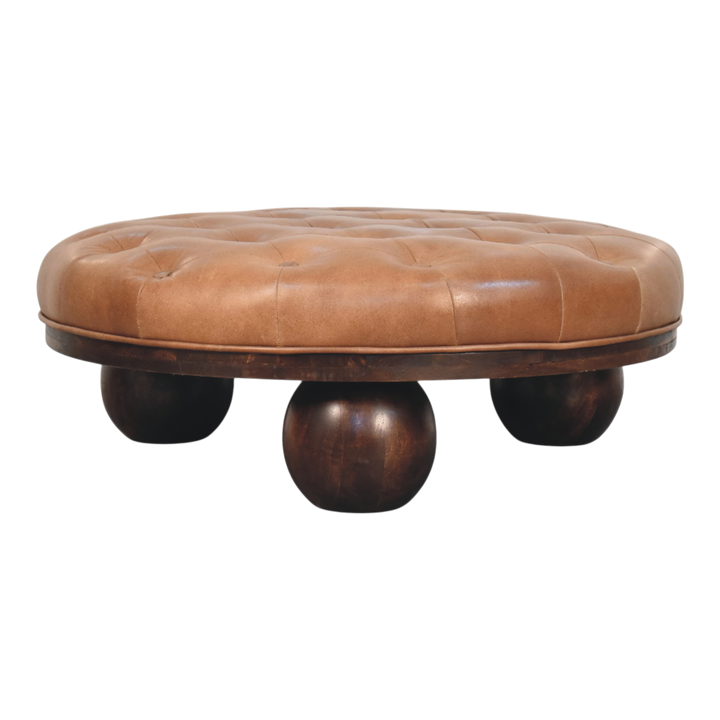 Lucca Round Leather Coffee Table in Burnt Caramel, front view. Tufted leather top in burnt caramel over a solid hardwood base, carved ball feet.