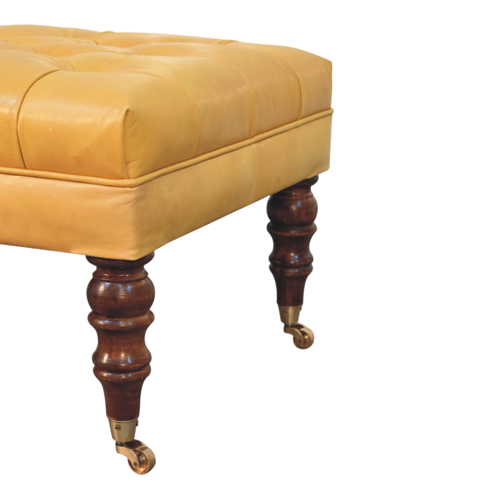 Close view of the brass castors on the Sussex Leather Ottoman in Blonde Saddle.