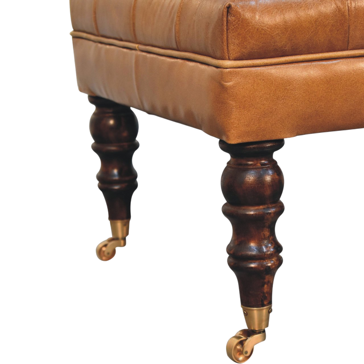 Close view of the turned legs and brass castors on the Sussex Leather Ottoman in Burnt Caramel.