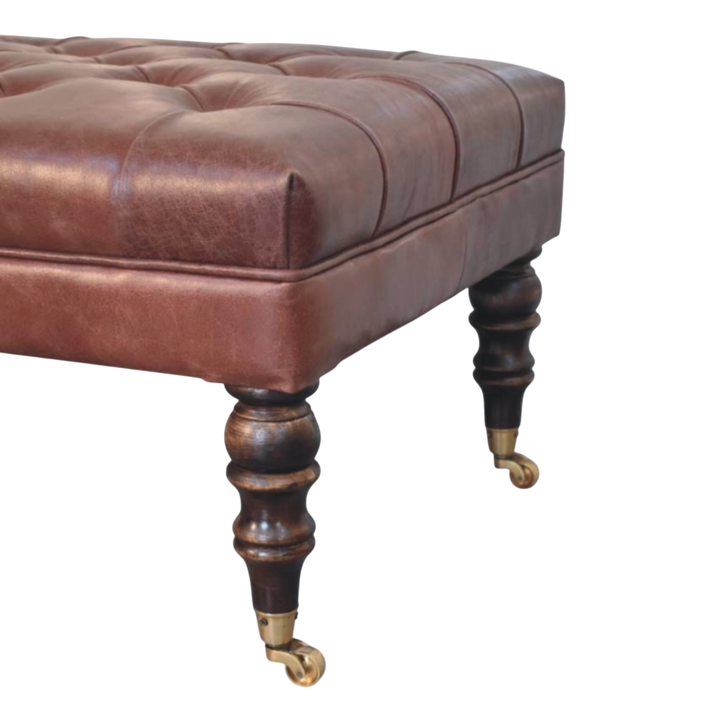 Close view of the turned legs and brass castors on the Sussex Leather Ottoman in Cognac.