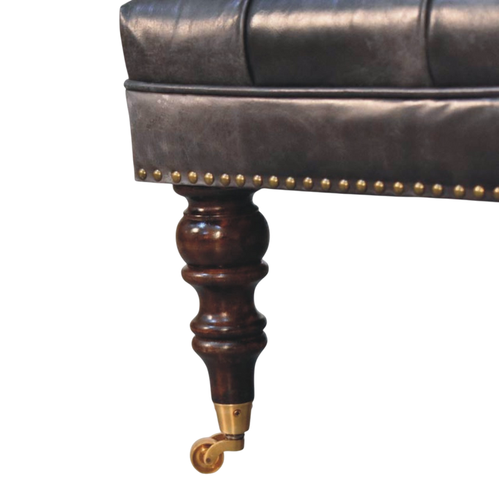 Close view of the turned legs and brass castors on the Sussex Square Leather Ottoman in Espresso.